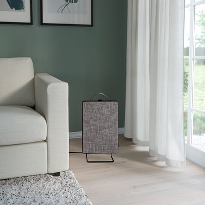 Living room with light green walls, cream armchair, and grey air purifier near window.