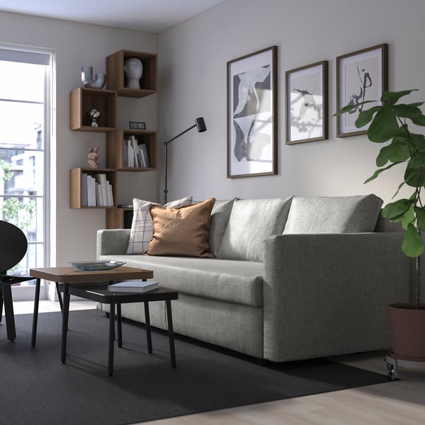 Modern living room with FRIHETEN sofa, cushions, coffee table, bookshelf, and wall art.