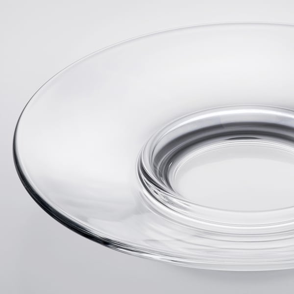 Clear glass saucer on a white surface, showcasing its smooth, transparent edge and durable design.