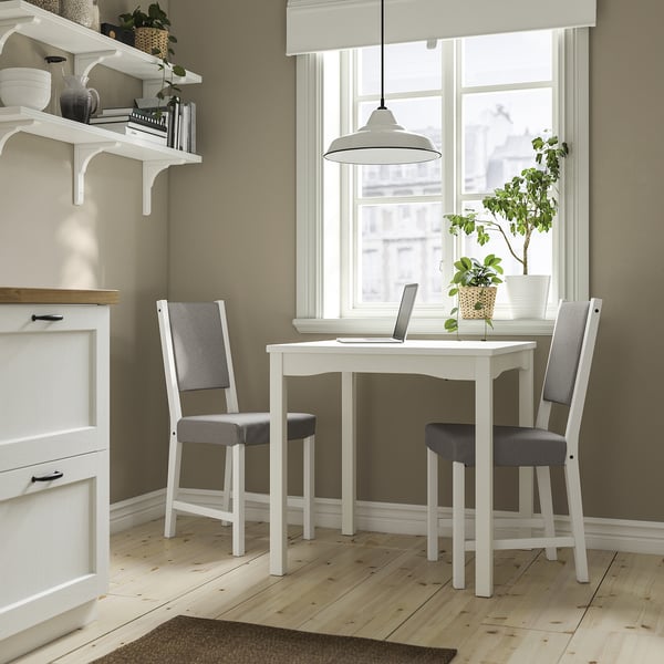 Kitchen nook with HAUGA table, chairs, window, plant, and laptop.