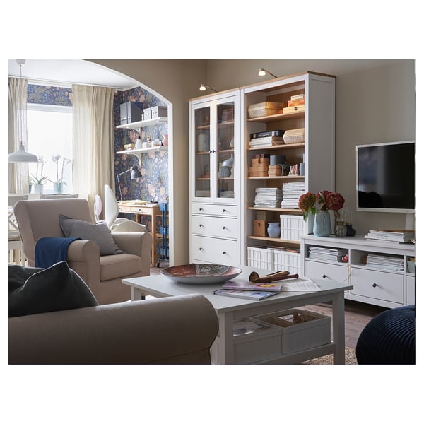 Modern living room with beige sofa, grey armchair, white cabinet, tv stand, and wooden table with decorative items.