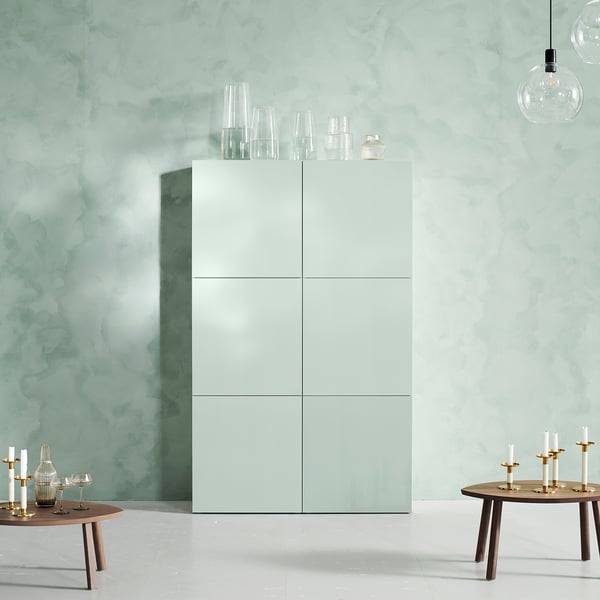 Minimalist room with white HJORTVIKEN cabinets, glass vases, and wooden tables with candles.