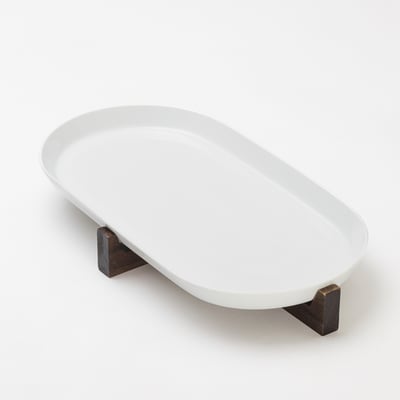 White ikea oval serving dish on dark wood stand.