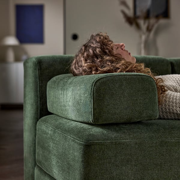 Person relaxing on green JÄTTEBO sofa, demonstrating comfortable seating with supportive cushions.