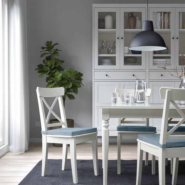 Small cosy dining setup with white JUSTINA chair pads, grey cushions, and modern decor.