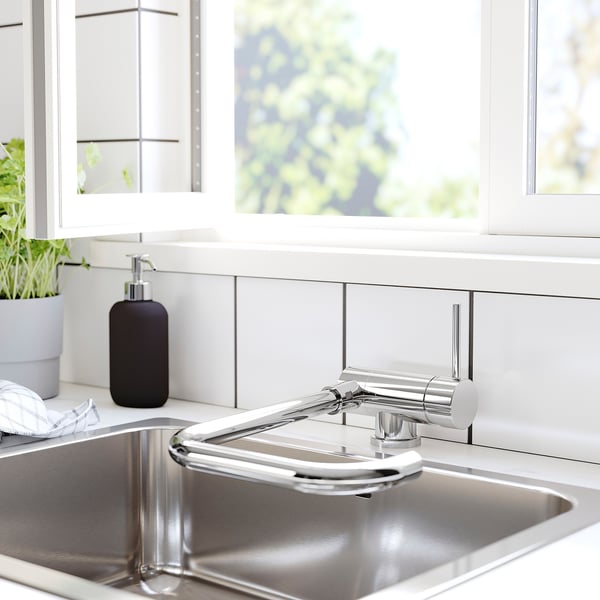 Modern kitchen sink with chrome JUTTERN tap and black dispenser. Clean, minimalist style with white cabinets.