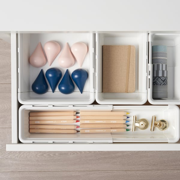 Organised drawer with art supplies. Coloured pencils, erasers, and other tools neatly arranged in extendable compartments.