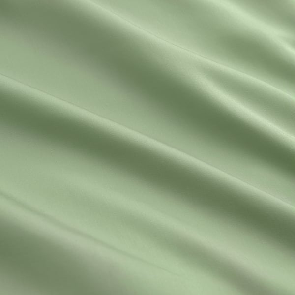 Smooth, lustrous green quilt cover, finely woven from lyocell, displaying elegant folds.