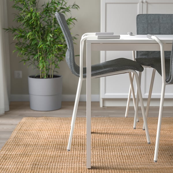 Minimalist office setup with modern, stackable chairs and a tall plant, promoting clean and efficient workspace.
