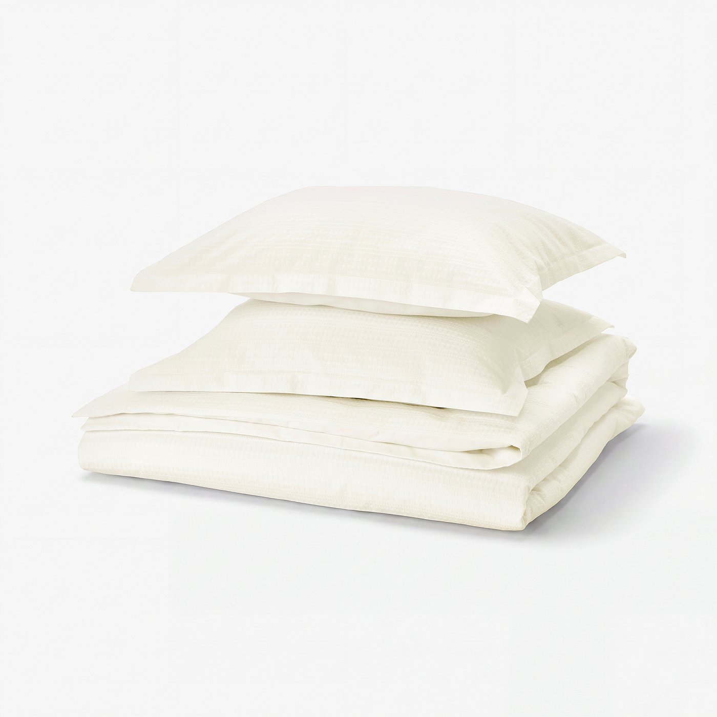Folded white cotton duvet cover set with waffle weave pattern. Three pieces stacked neatly.