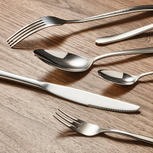 Silverware set on wood, including knife, fork, and spoons, showcasing sleek, durable design and reflective surfaces.