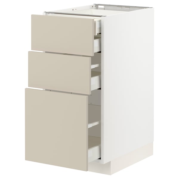 A white METOD kitchen cabinet with beige drawers in a minimalist design.