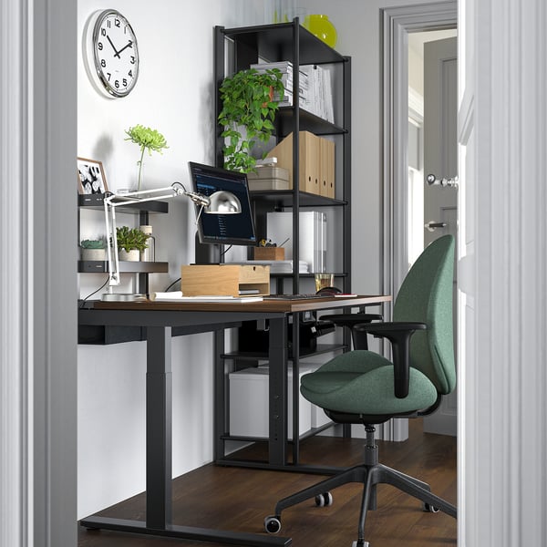 Modern home office setup with wooden desk, green chair, and black metal frame, optimised for workspace efficiency.