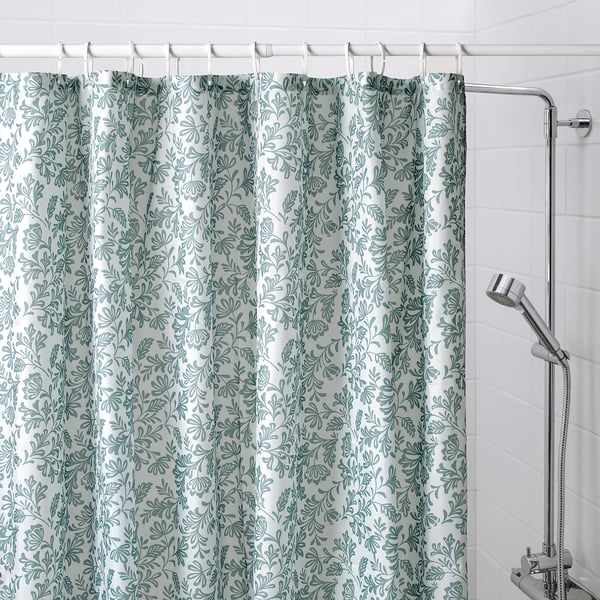 A NAPELTYNNE shower curtain in grey-turquoise, made from recycled polyester. It a leafy pattern and proves larger than the shower fixture beside it.