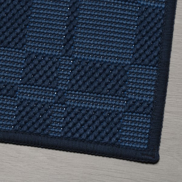 Close-up of a textured blue rug on wooden floor