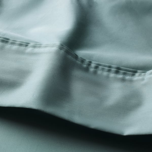 Soft, smooth bedsheet with a subtle sheen, showcasing a pleated edge and a pleasing blue-green hue.