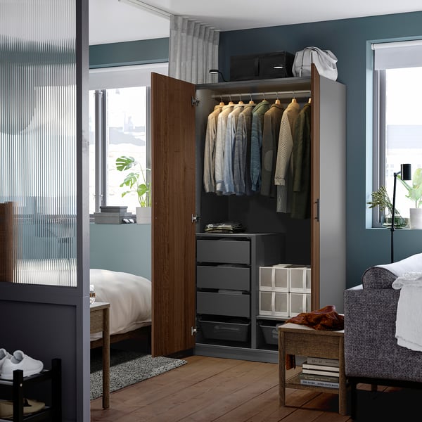 Open wooden wardrobe displaying shirts, drawers, and accessories; mounted tv above.