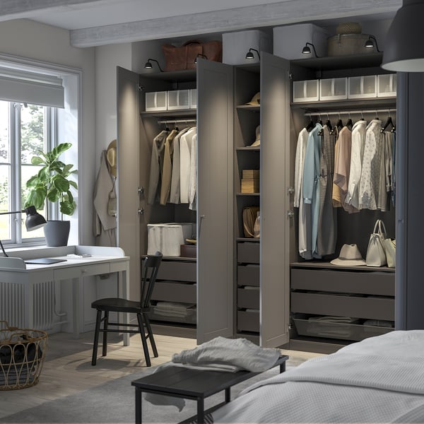 Open wardrobe with organised clothes, shelves, and drawers, lit by integrated lighting.