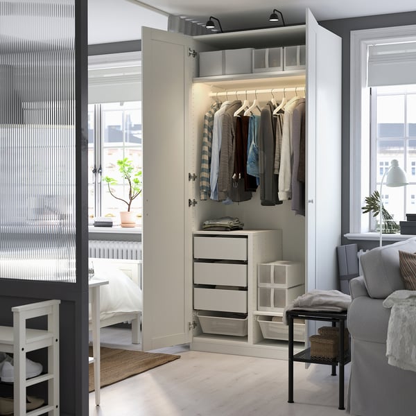 Modern wardrobe with clothes hangers, drawers, and baskets. Interior lighting illuminates the storage space.