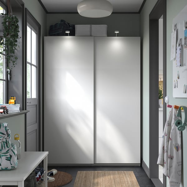 Modern closet with sliding doors. White doors, grey walls, built-in lighting, and a rug.