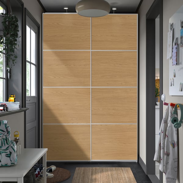 Large oak PAX wardrobe with sliding doors, central between doorway and shelves, with overhead pendant light.