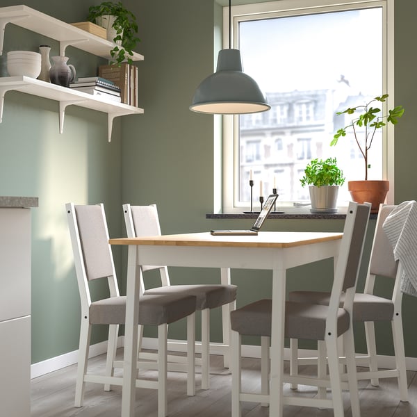 Small cosy dining setup with white table and grey chairs, decorated with green plants, under a blue pendant light.
