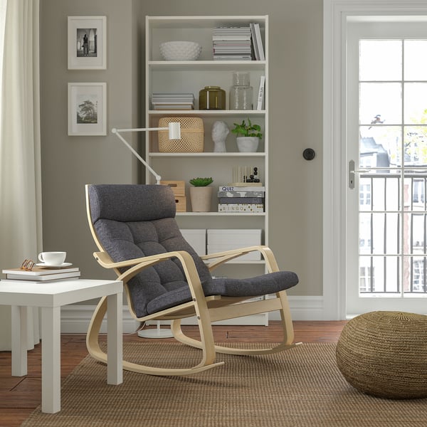 Modern living room with POÄNG rocking chair, wooden frame, and large cushions near window.