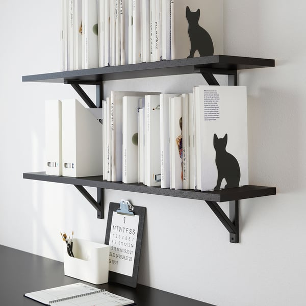 Black cat-shaped bookends on shelves, holding white books upright.