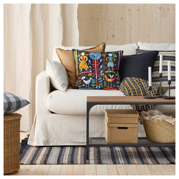 Living room with white sofa, colourful pillows, striped rug, and wooden walls.