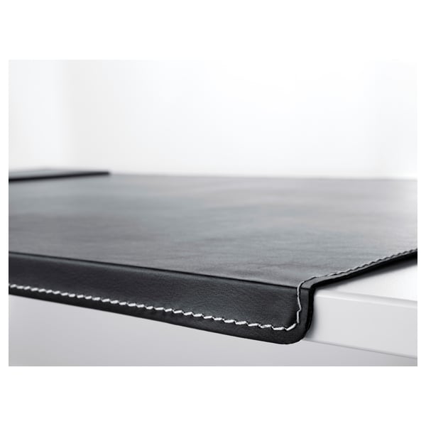 Close-up of black desk pad with stitched edge, smooth surface showcasing quality material.