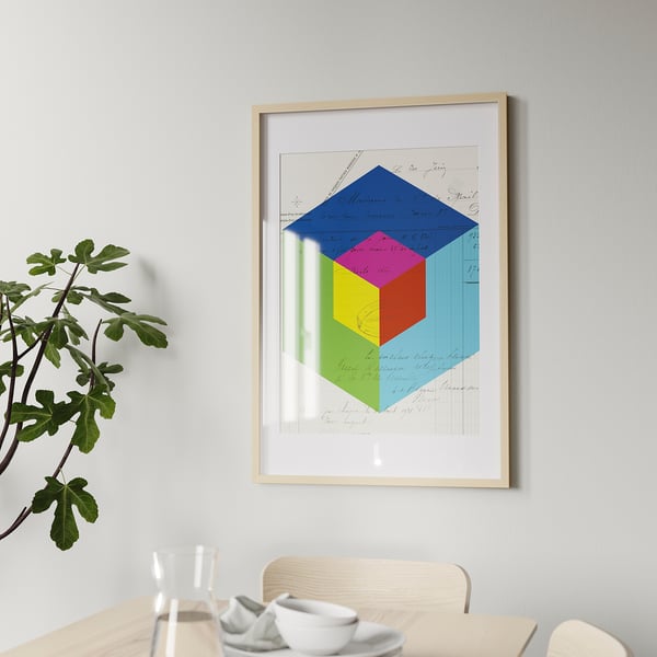 Framed picture on wall with vibrant geometric design. Below, a wooden table holds white plates and glasses, accompanied by a green plant.