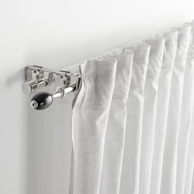 Curtain rod bracket holding rods together. White curtains draped over, displaying connector functionality.