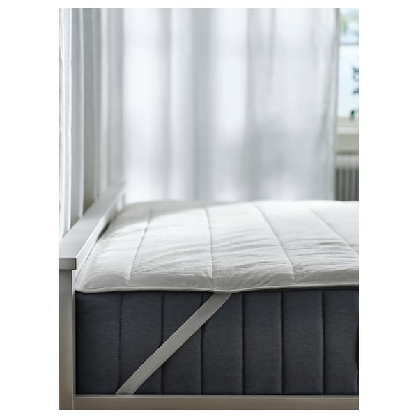 A white ROSENVIAL mattress protector with elastic straps, placed on a dark mattress, ensuring comfort and protection.