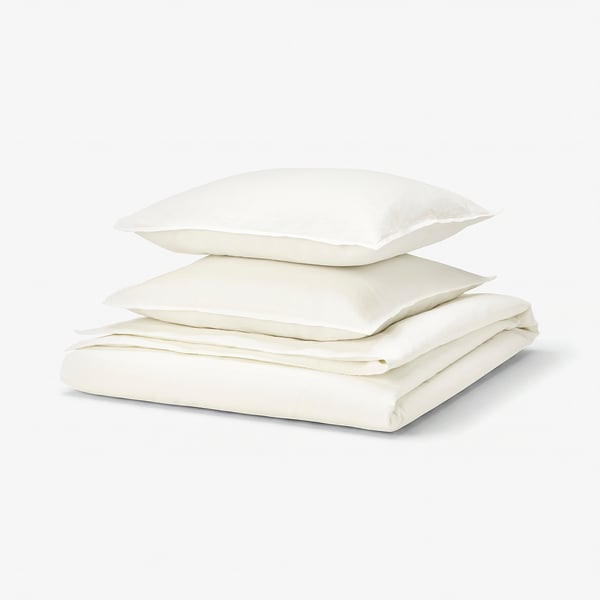 Displays a stack of white bed linens, including a duvet cover and pillowcases, neatly folded and stacked, with a simple, clean design.