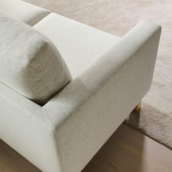Modern sofa with sleek, light grey upholstery and wooden legs, designed for comfort and easy cleaning.