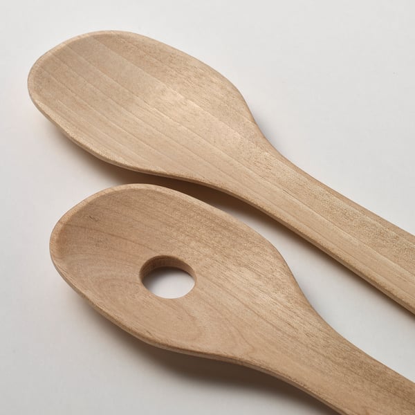 Two wooden salad servers made of birch, displayed on a light-colored surface, showcasing their smooth, rounded, and natural finish.