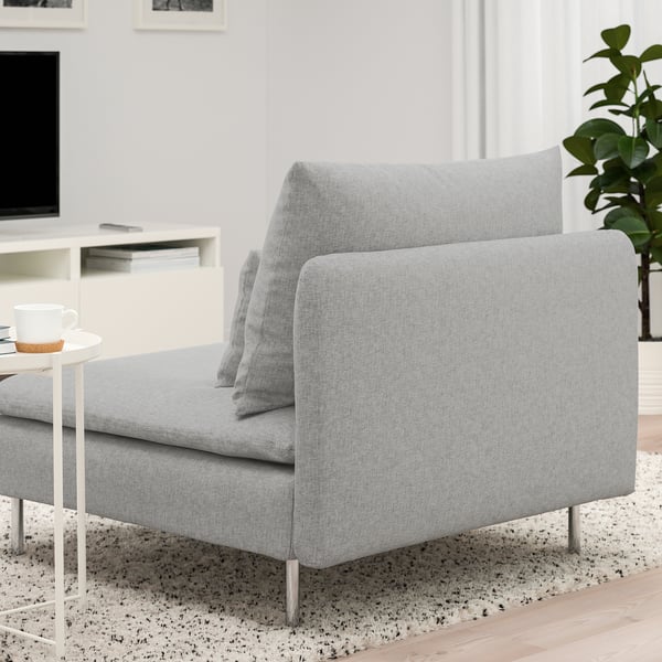 Modern grey couch on rug with coffee table & plant, tv in background.