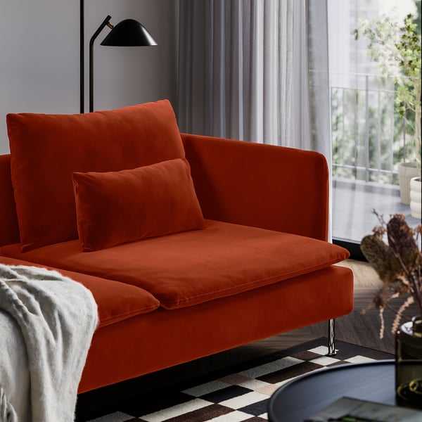 Bright orange velvet sofa with cushions in a cosy living room.