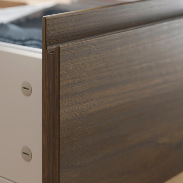 Wooden drawer edge close-up. Part of a simple, sturdy bed frame with roller drawers for hidden storage.