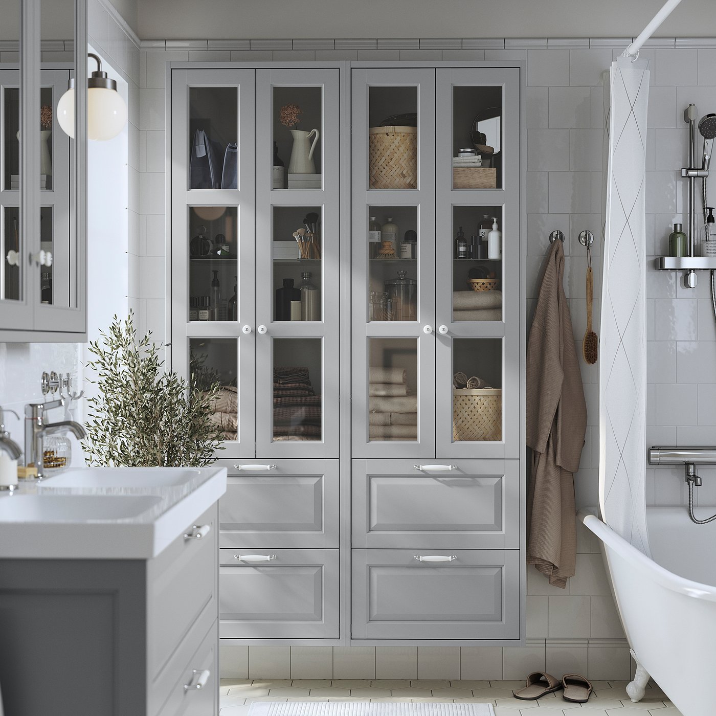 Grey TÄNNFORSEN cabinet with glass doors and drawers in bathroom next to bathtub and sink.