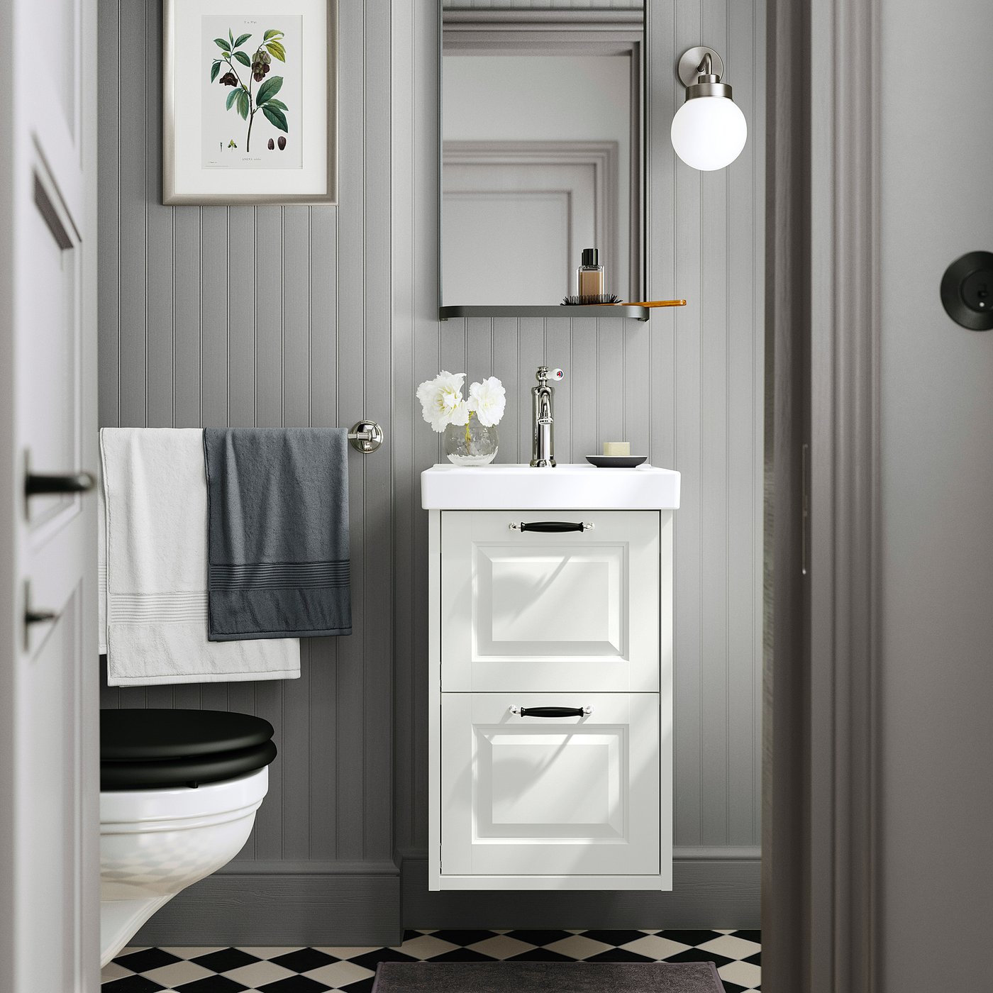 Modern bathroom with TÄNNFORSEN vanity, black toilet, grey towels, chequered floor, and wall mirror.