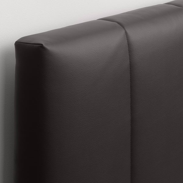 Close-up of a modern, padded, black headboard with neat stitching, showcasing its high-quality fabric and design.