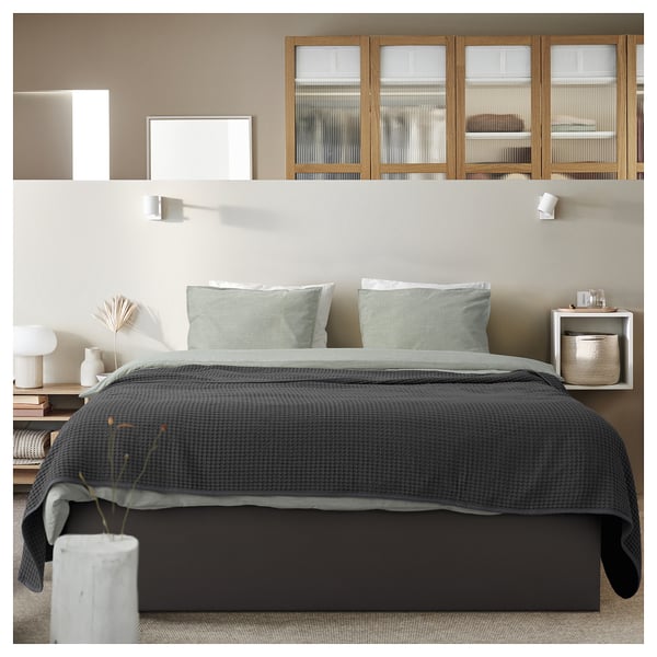 Modern grey bed with storage, textured fabric, wooden accents, sleek lines.