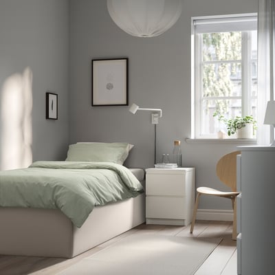 Modern minimalist bedroom with TJÅLLE bed, green bedspread, plant, pendant lamp, and large window.