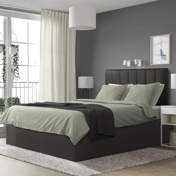 Modern bedroom with TJÅLLE bed, dark walls, large window & plants.