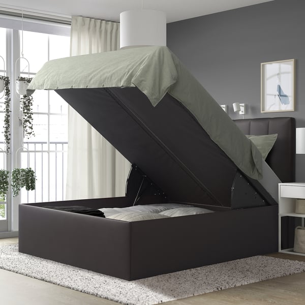 Modern bedroom with TJÅLLE bed, grey, large, storage, plush headboard, white rug, hanging plants, white walls, grey curtains, and art.