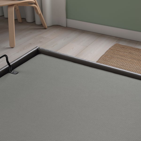 Modern grey mesh storage box on wooden floor, near chair and rug, quality design.