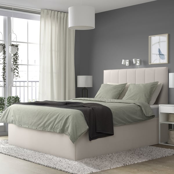 Minimalist bedroom with grey TJÅLLE bed, dark wall, plants, lamp, art.