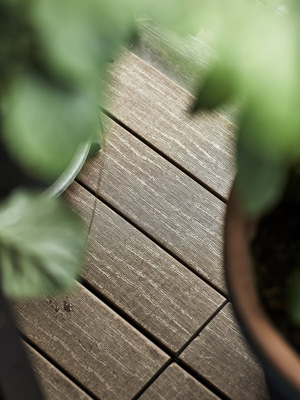 Wooden deck boards in natural brown, surrounded by green leaves.
