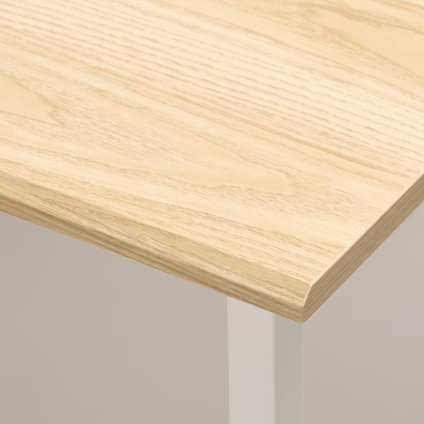 Close-up of smooth, light wood tabletop corner, showcasing quality finish.